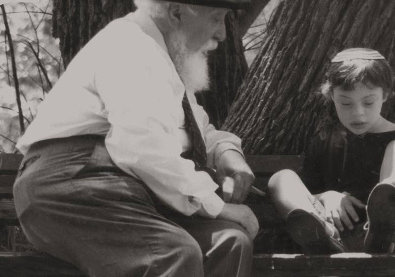 Professor Feuerstein sitting on a garden bench beside a small child