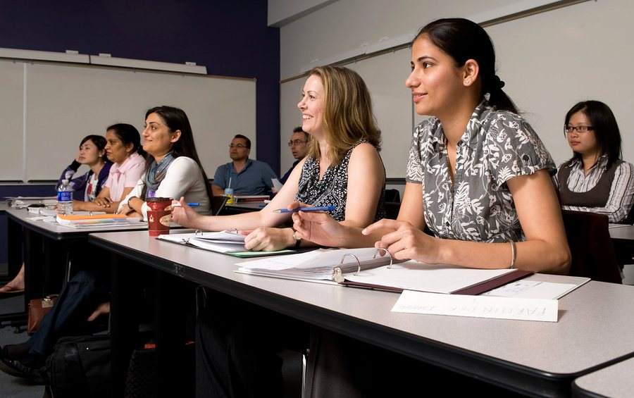 Adults in a continuing-education class, listening and taking notes