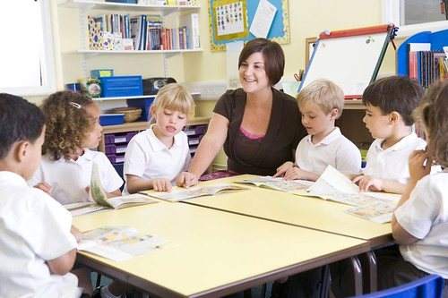 A teacher reading with a small group of young children around a low table
