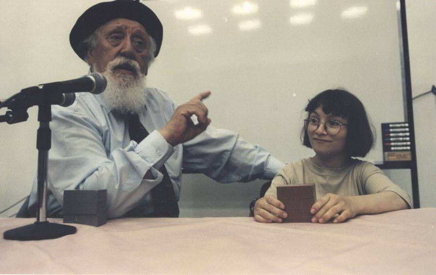 Professor Feuerstein teaching a class, beside a smiling girl holding a puzzle