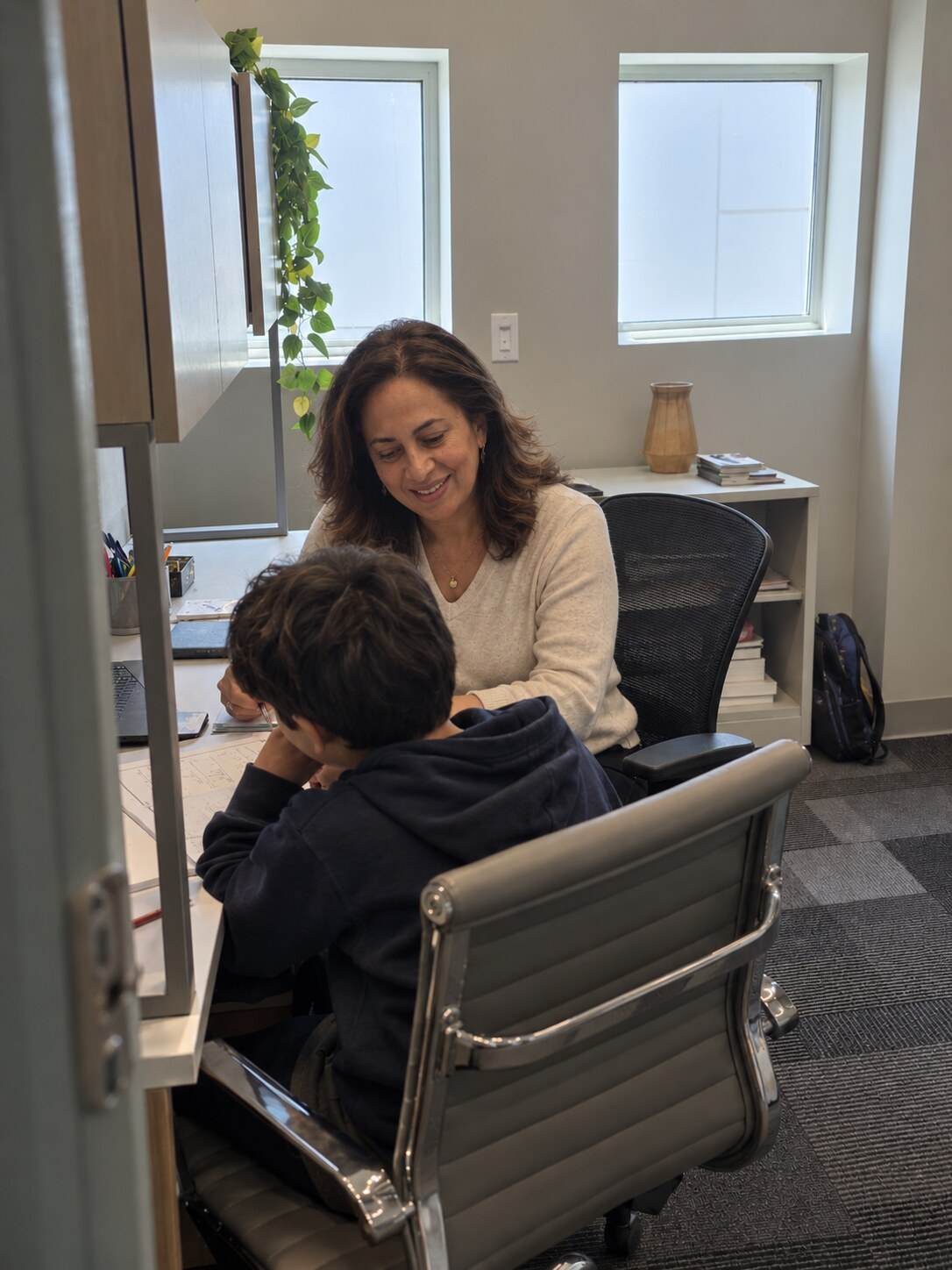 Nereida working one-on-one with a young learner at a desk in her office