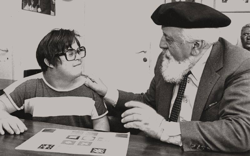 Professor Feuerstein, hand on a boy’s shoulder, talking him through an exercise sheet