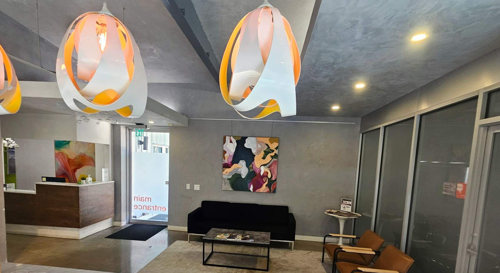 The lobby of The Village Suites: a sofa, leather armchairs and bright pendant lamps